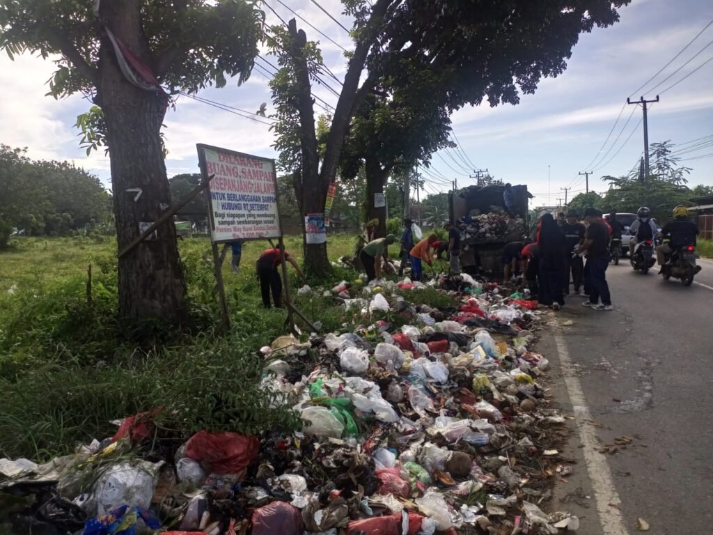 Aparatur Desa Way Huwi gotong royong membersihkan sampah yang di buang sembarangan oleh warga di jalan Airan Raya, Way Huwi, Jatiagung, Lampung Selatan